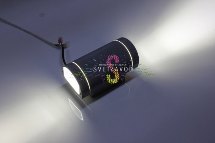 Крупный план двухстороннего светодиодного прожектора в сером металлическом корпусе с полукруглым рассеивателем, видна маркировка и крепление