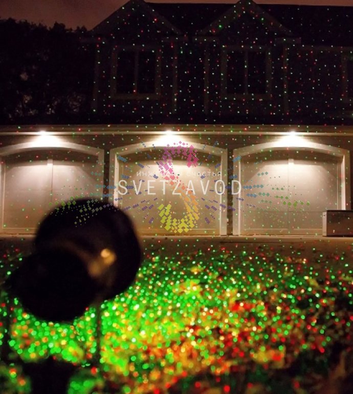 Лазерный проектор Garden X-30 Premium (X-38) в работе, создает зеленые и красные лазерные узоры анимации 'Светлячок' на стене, установлен на грунтовом основании.