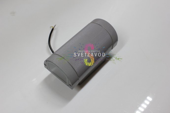 Крупный план двухстороннего светодиодного прожектора в сером металлическом корпусе с полукруглым рассеивателем, видна маркировка и крепление