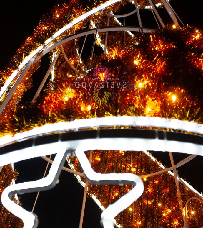 Крупный план светодиодной елки Конус с золотой мишурой, стальным каркасом и теплым белым свечением, установленной на улице.