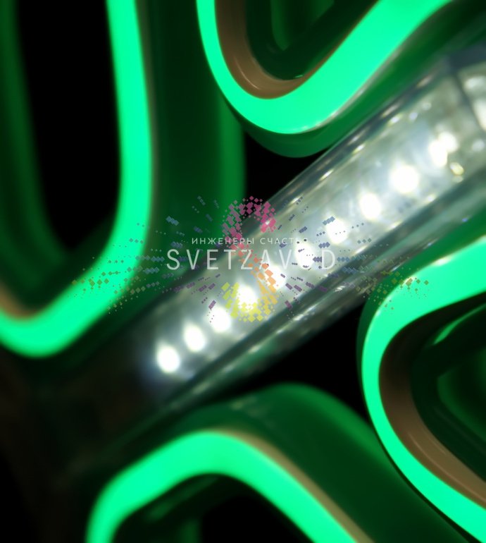 Крупный план зеленой светодиодной снежинки 40 см с неоновым свечением и эффектом тающих сосулек, установленной на фасаде здания.