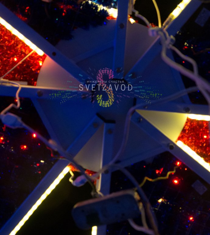 Детальное фото световой конструкции Подарок 300х300х400 см. Виден прочный стальной каркас, светодиодные гирлянды, мишура и бант. Конструкция предназначена для уличного использования.