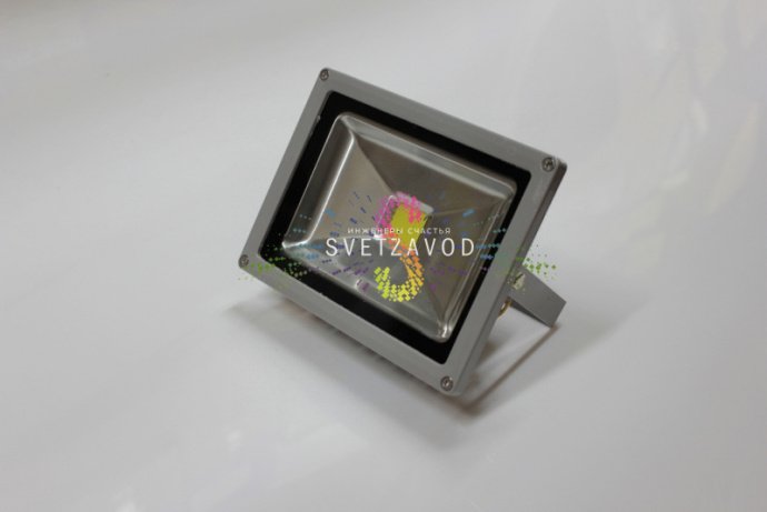 Крупный план синего светодиодного прожектора мощностью 20Вт в сером алюминиевом корпусе с крепежными элементами и прозрачным стеклянным рассеивателем.