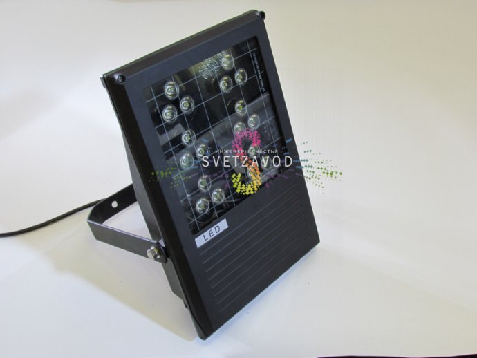 Крупный план серого металлического корпуса поворотного светодиодного прожектора с прозрачным стеклянным рассеивателем и крепежным элементом.