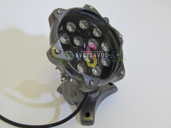 Крупный план серого точечного поворотного светодиодного прожектора с металлическим корпусом, стеклянным рассеивателем и креплением для накладного монтажа.