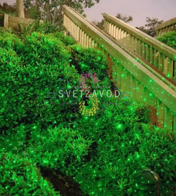 Лазерный проектор Garden X-30 Premium (X-38) в работе, создает зеленые и красные лазерные узоры анимации 'Светлячок' на стене, установлен на грунтовом основании.