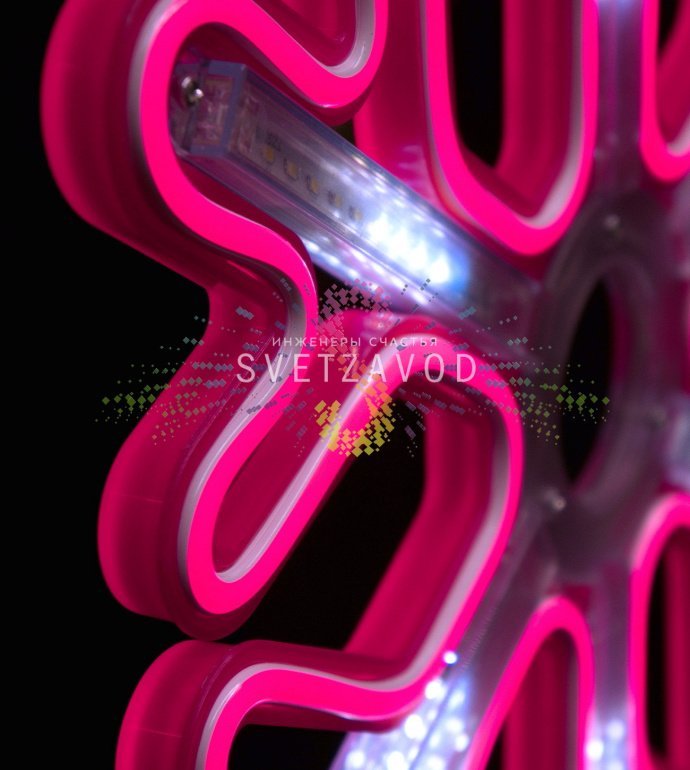 Крупный план розовой светодиодной снежинки из гибкого неона на пластиковом каркасе, демонстрирующий эффект плавно стекающих сосулек. Видно крепежное ушко и кабель питания.