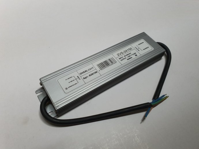 Детальное изображение металлического блока питания 24В 150W IP67 с герметичными кабельными вводами, крепежными отверстиями и этикеткой с характеристиками: вход 220В, выход 24В, 150W, степень защиты IP67.